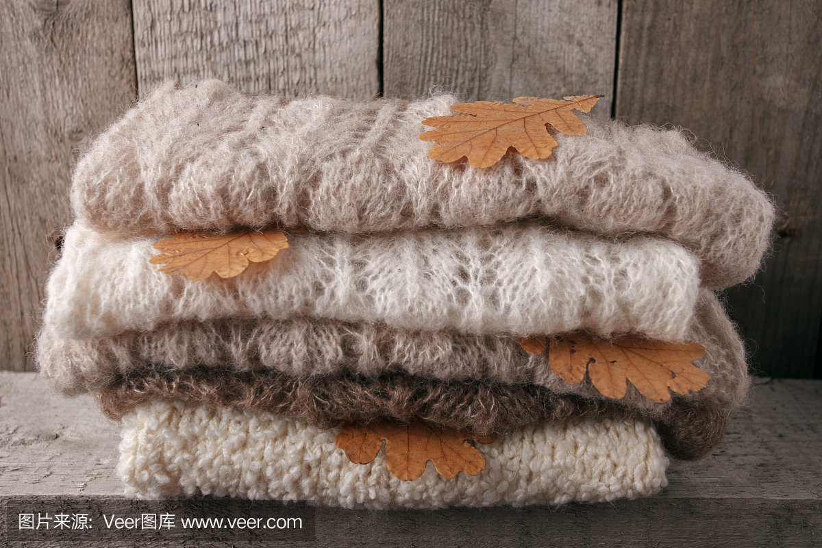 背景与暖和的毛衣。堆着秋叶的针织衣服,温暖的背景,针织品,文字的空间,秋冬的概念。本空间